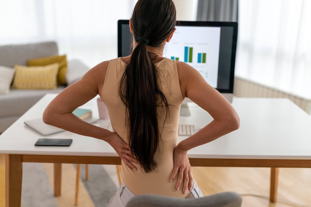 Woman feeling lower back pain from sitting at a desk for long hours