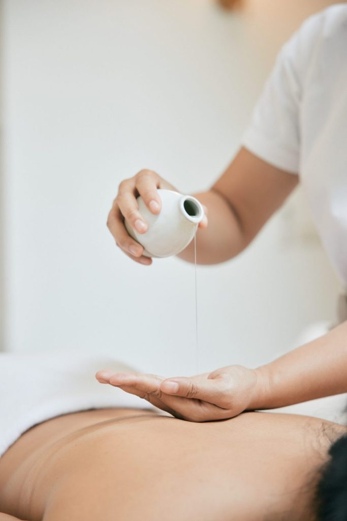 A therapist performing an aromatherapy massage with warm oil on a guest at a boutique Bangkok spa.