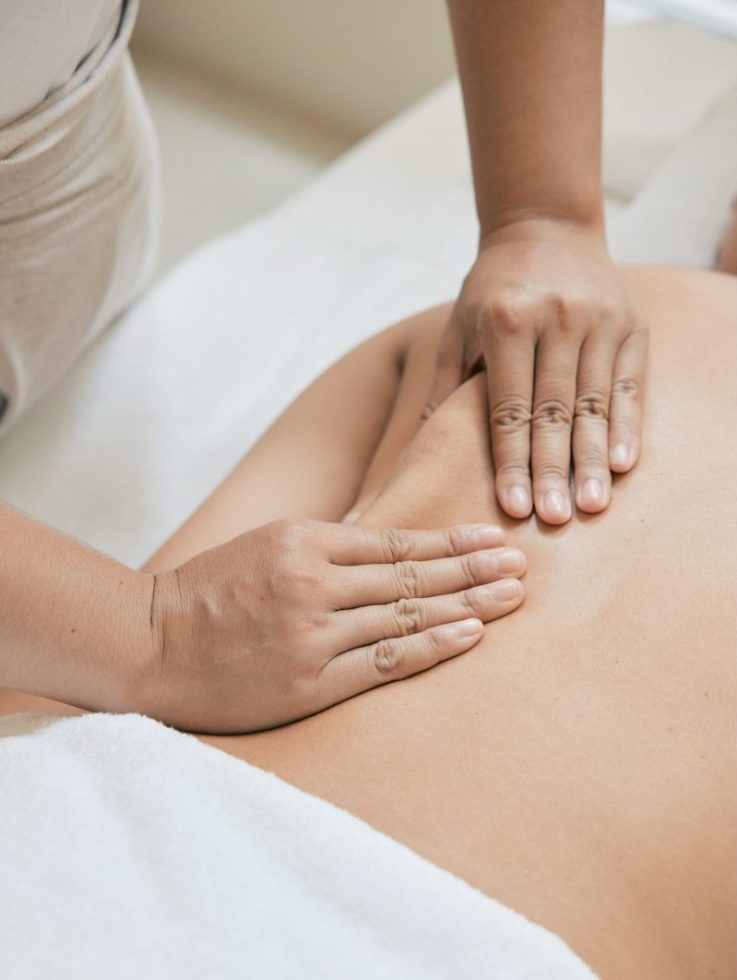 Therapist performing lymphatic drainage massage on a client’s back.